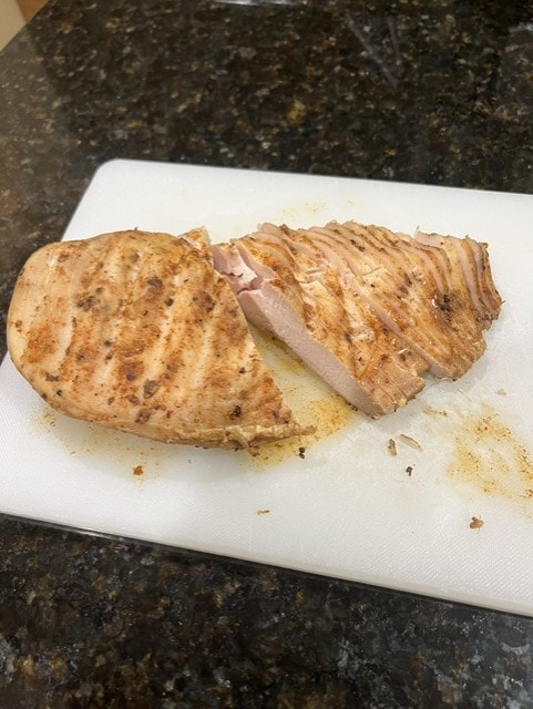 Grilled chicken breast sliced on a cutting board seasoned with Monty's Backyard Legend rub
